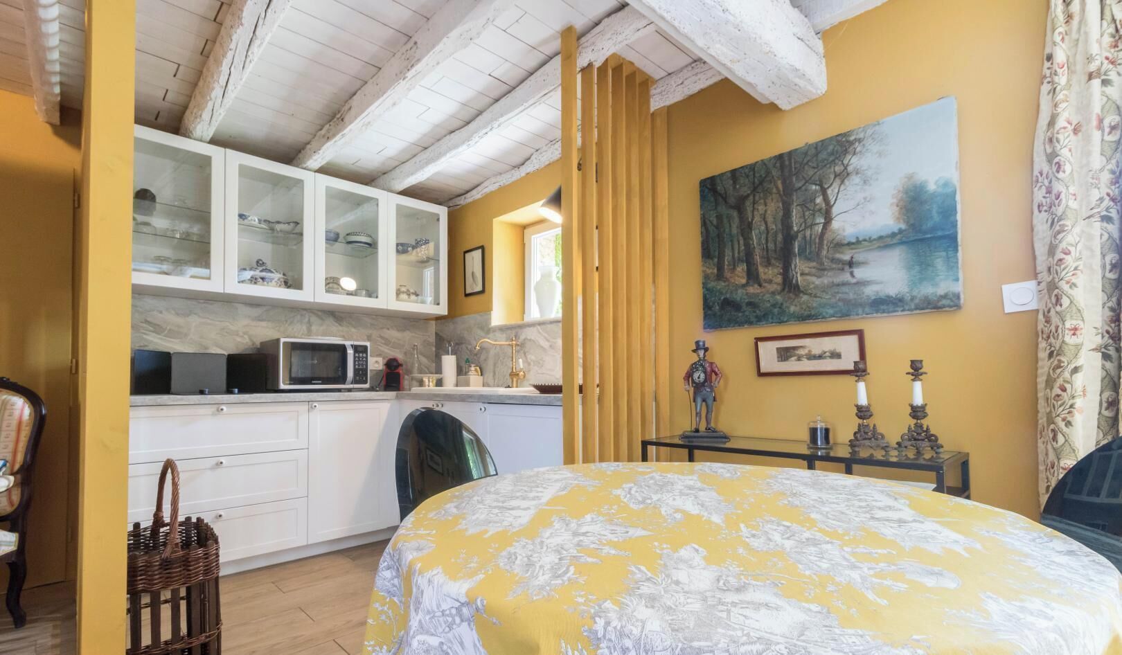 Une pièce comprenant un lit, un coin cuisine et un tableau accroché au mur.