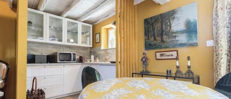 Una habitación con una cama, una zona de cocina y un cuadro en la pared.