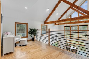 A spacious room with a wooden ceiling, a white sofa, a small table, and a potted plant. - Snow Creek: Luxury New-Build Chalet, Amazing Spot (Stowe)