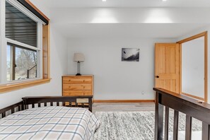 A bedroom with a bed, a dresser, a nightstand, a window, a door, and a wall-mounted picture. - Snow Creek: Luxury New-Build Chalet, Amazing Spot (Stowe)