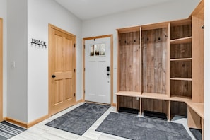 A hallway with a wooden door, a coat rack, and a bench with shelves. - Snow Creek: Luxury New-Build Chalet, Amazing Spot (Stowe)