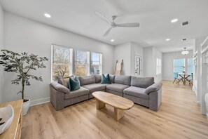 A modern living room with a sectional sofa, a wooden coffee table, and a ceiling fan. - Sandbar Drift - Where the Coast Slows Down. (Laguna Beach)