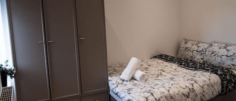 A bedroom with a bed, a wardrobe, and a small plant.
