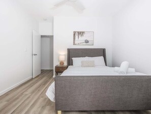 Ein Schlafzimmer mit einem Bett, einem Nachttisch, einer Lampe und einem Wandbild.