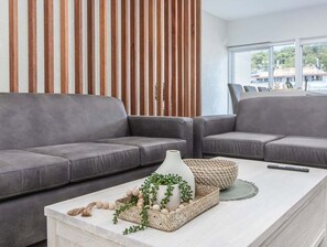 A modern living room with two grey sofas, a white coffee table with decorative items, and a wooden slatted wall. - The Laneway Villas - Central Apartments in the heart of Burleigh Heads - Unit 4 (Gold Coast)