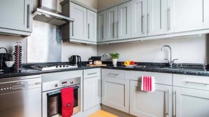 Una cucina moderna con elettrodomestici in acciaio inossidabile, mobili bianchi e un piano di lavoro nero.