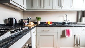 Una cucina moderna con un fornello a gas, una macchina del caffè e una pianta sul piano di lavoro.