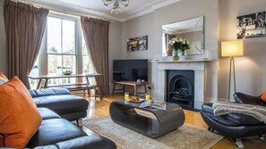 Ein Wohnzimmer mit Sofa, Couchtisch, Kamin und Fernseher.