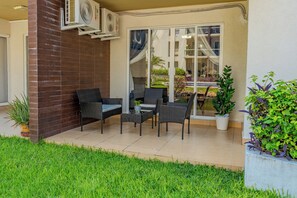 An outdoor patio area with a brick wall, two wicker chairs, a small table, and a potted plant. - Acapulco Getaway Pool & Jacuzzi 2 BR (Acapulco de Juárez)