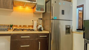 A kitchen with a stainless steel refrigerator, wooden cabinets, a gas stove, and a countertop with a blender and a paper towel holder. - Acapulco Getaway Pool & Jacuzzi 2 BR (Acapulco de Juárez)