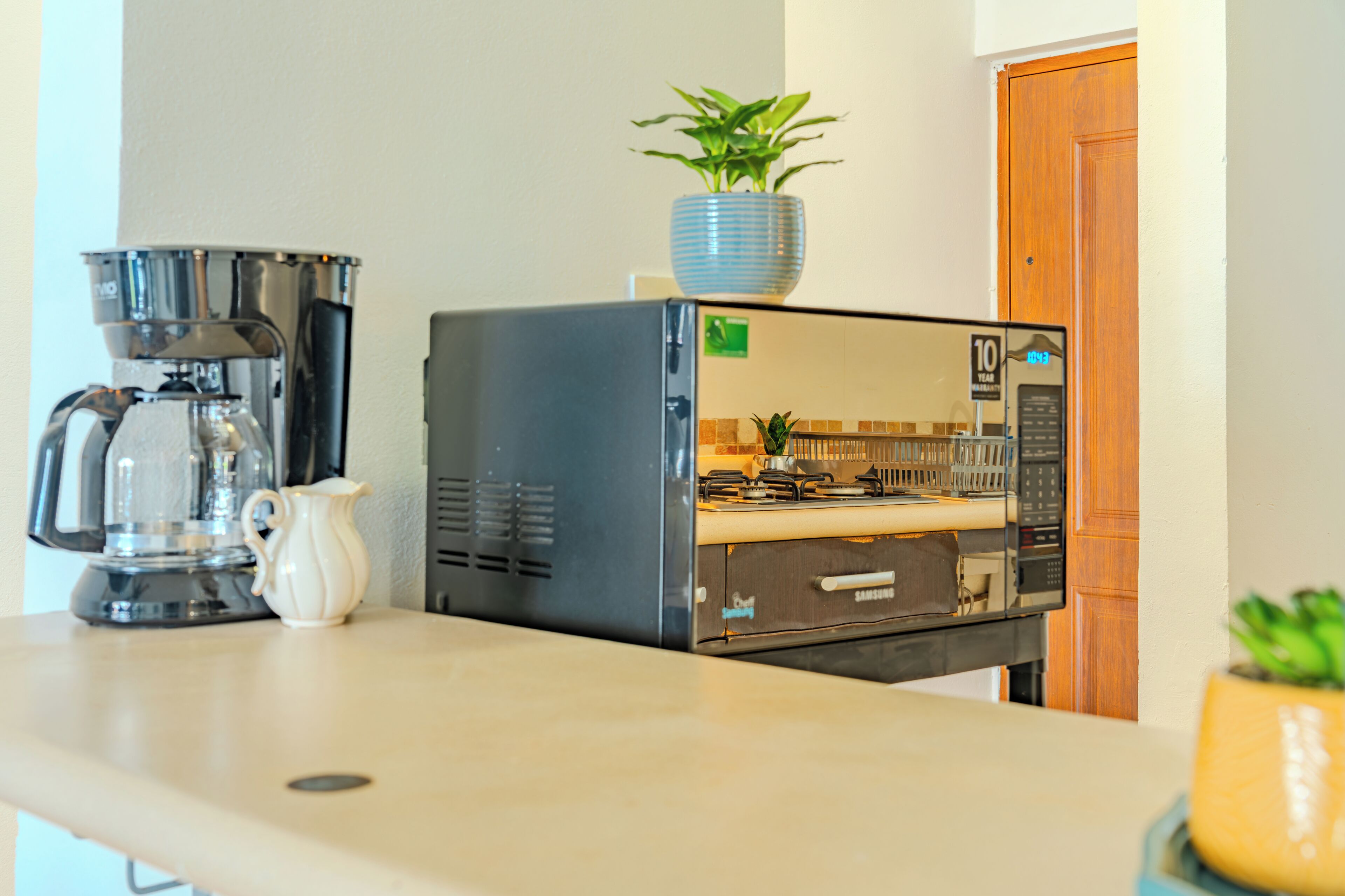 Uma cozinha compacta equipada com cafeteira, micro-ondas e fogão.
