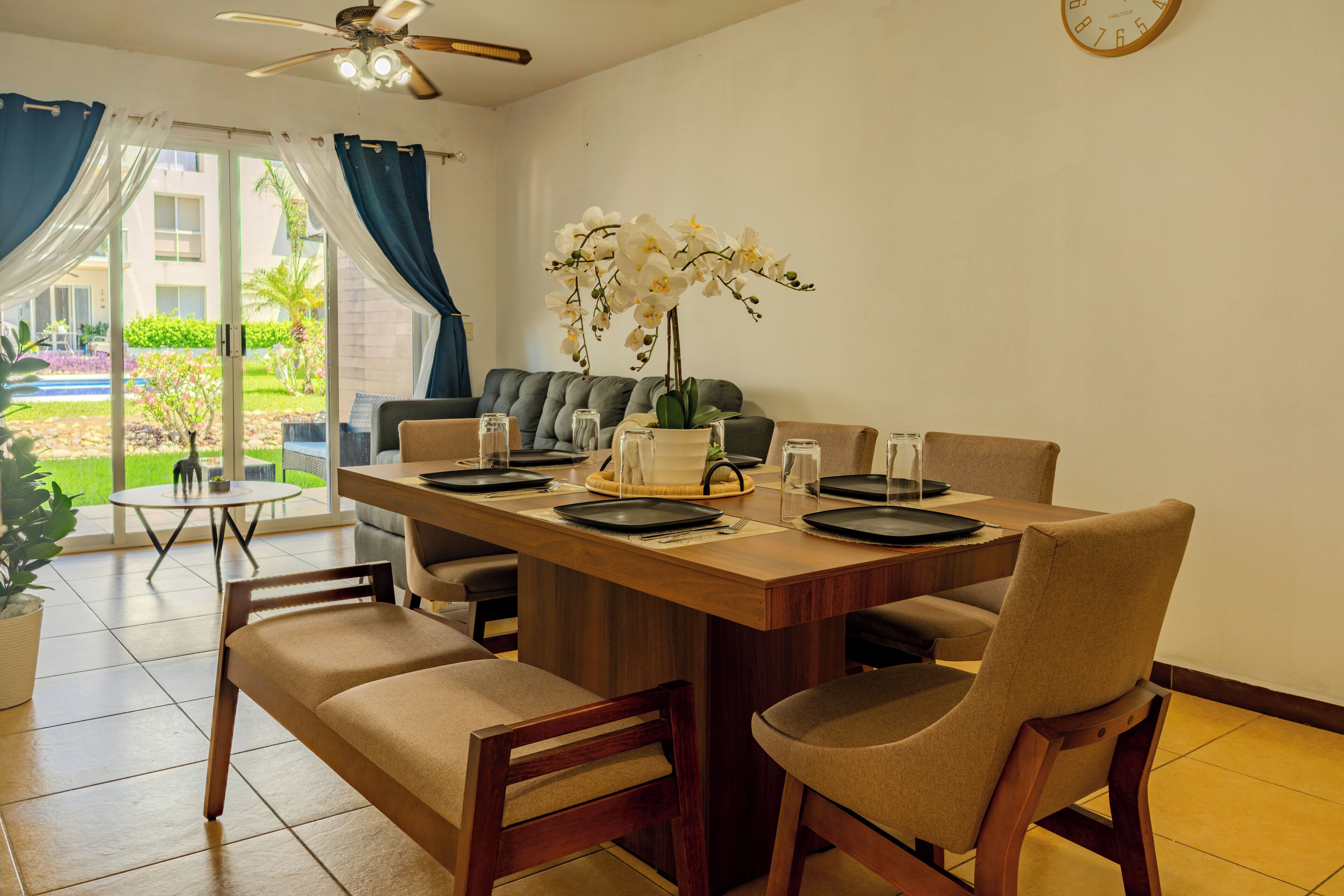 A dining area with a wooden table set for four, surrounded by chairs.