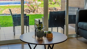 A modern interior with a round table, potted plants, and a view of a garden through glass doors. - Acapulco Getaway Pool & Jacuzzi 2 BR (Acapulco de Juárez)