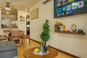 A living room with a flat-screen TV mounted on the wall displaying various apps. There is a dining area with a table and chairs, and a kitchen visible in the background. - Acapulco Getaway Pool & Jacuzzi 2 BR (Acapulco de Juárez)