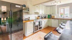 Eine moderne Küche mit Kühlschrank, Backofen, Mikrowelle und einem Essbereich mit Tisch und Stühlen.