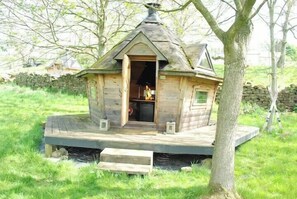 Eine Holzhütte mit geneigtem Dach, einer kleinen Veranda und einem Schornstein.