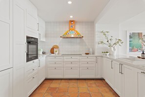 Una cocina moderna con armarios blancos, horno empotrado y un salpicadero colorido.