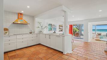A modern kitchen with white cabinets, a colorful backsplash, and a view to a patio with outdoor seating.