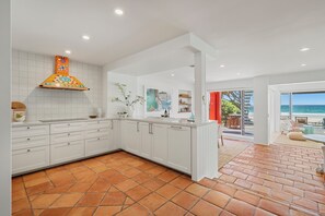 A modern kitchen with white cabinets, a colorful backsplash, and a view to a patio with outdoor seating. - The Beachhouse by Sandbox - Entire Luxury Beachfront Home with Sauna and Steam Shower in Palm Beach (Palm Beach)