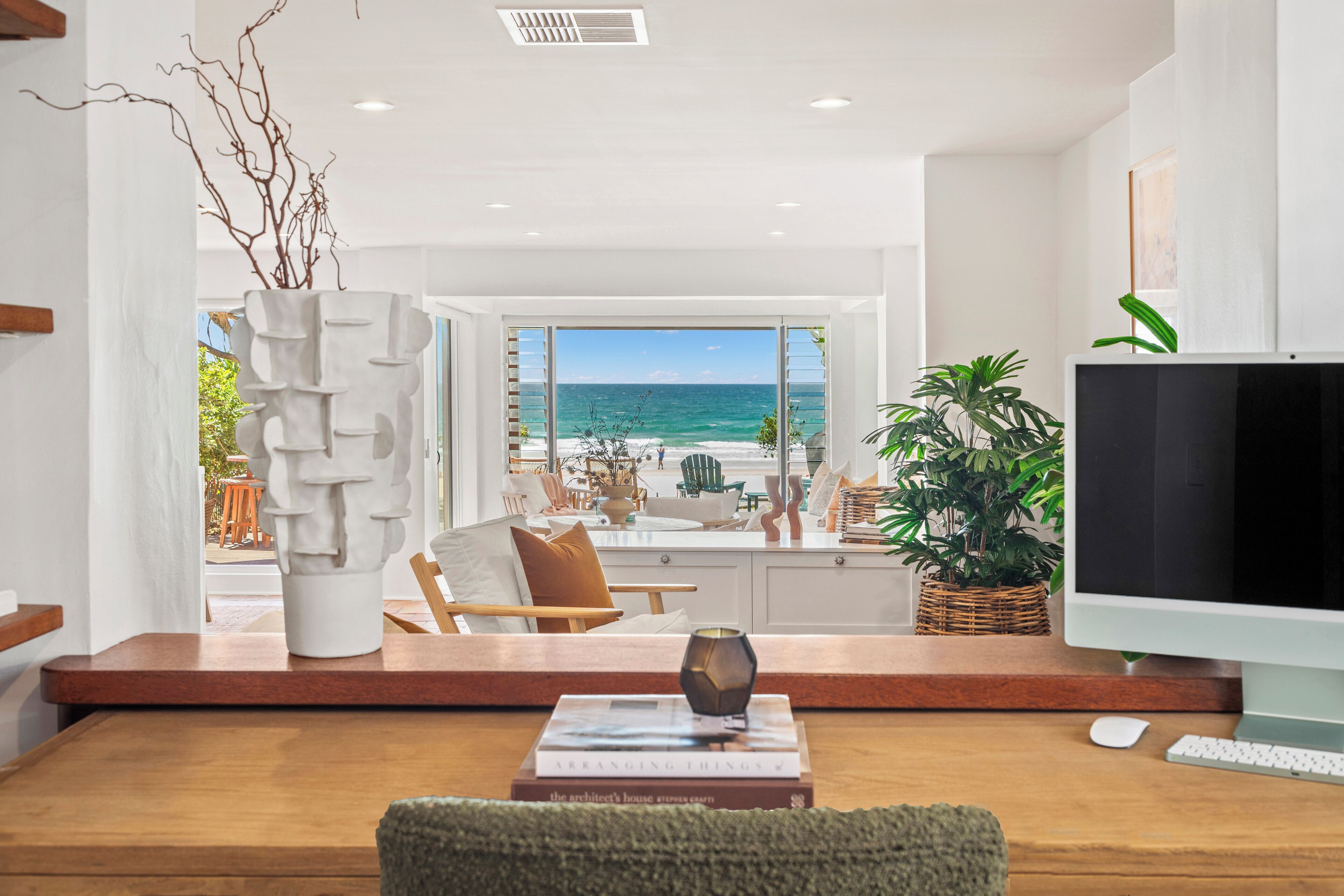 A modern living room with a view of the ocean, a flat-screen TV, and a cozy seating area.