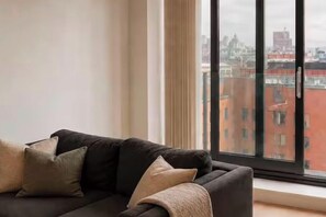 Ein modernes Wohnzimmer mit einer schwarzen Couch und einem großen Fenster mit Blick auf die Stadt.