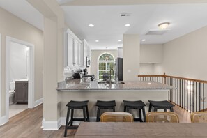 Eine moderne Küche mit einer zentralen Kochinsel, Barhocker und einem Esstisch.