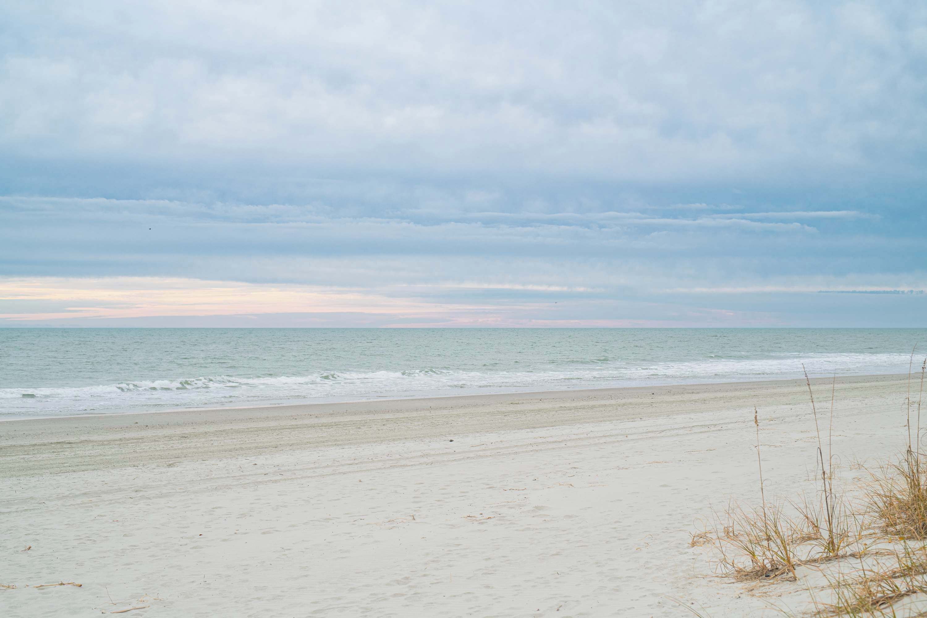A beach with a wide sandy shore and the ocean in the background.