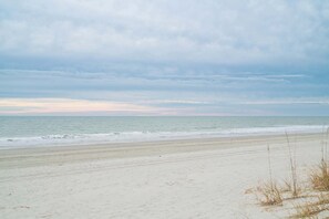 Ein Strand mit breitem Sandstrand und dem Meer im Hintergrund.
