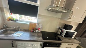 A compact kitchen with a washing machine, an oven, a microwave, and a sink.