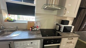 A compact kitchenette with a built-in washing machine, a microwave, and a stove.