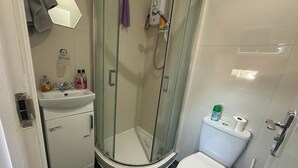 A bathroom with a glass-enclosed shower, a toilet, and a sink.