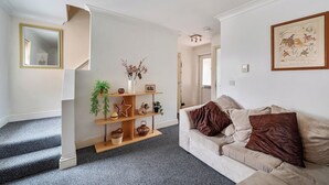 A living room with a sofa, a coffee table, and a fireplace. There is a staircase leading to another room. - 3 Bed - Sleeps 6 - Parking - Central Canterbury (Canterbury)