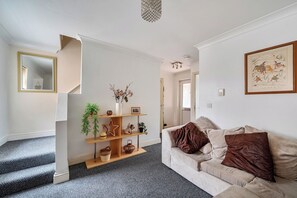 A living room with a sofa, a coffee table, and a fireplace. There is a staircase leading to another room. - 3 Bed - Sleeps 6 - Parking - Central Canterbury (Canterbury)