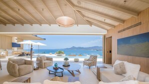 A spacious living area with a view of the sea, featuring a high ceiling, modern furniture, and a large painting on the wall. - Casa Yeiy 7BD - Kupuri Punta Mita (Punta de Mita)