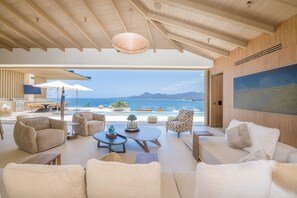 A spacious living area with a view of the sea, featuring a high ceiling, modern furniture, and a large painting on the wall. - Casa Yeiy 7BD - Kupuri Punta Mita (Punta de Mita)