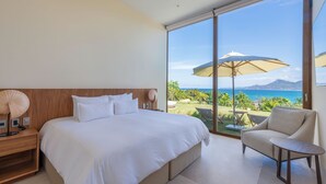 A bedroom with a large bed, a nightstand, a lamp, and a view of the ocean through a sliding glass door. - Casa Yeiy 7BD - Kupuri Punta Mita (Punta de Mita)