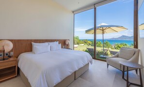 A bedroom with a large bed, a nightstand, a lamp, and a view of the ocean through a sliding glass door. - Casa Yeiy 7BD - Kupuri Punta Mita (Punta de Mita)