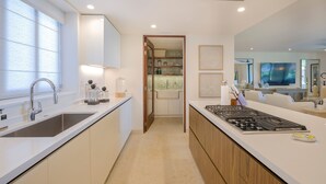 Una cocina moderna con una isla central, horno empotrado y un amplio ventanal que proporciona luz natural.