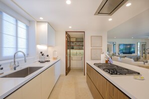 A modern kitchen with a central island, a built-in oven, and a large window providing natural light. - Condo Ginger 3BD - Tau Punta Mita (Punta de Mita)