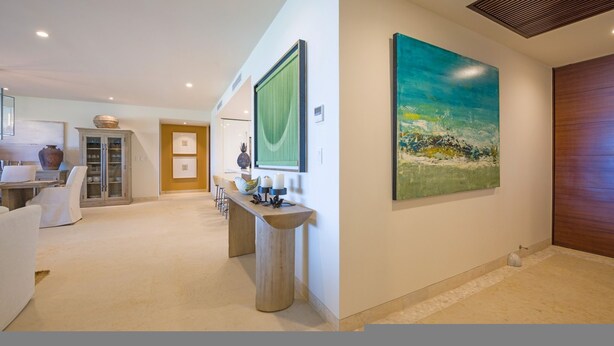 Un interior moderno con una zona de comedor, una cocina y un cuadro grande en la pared.