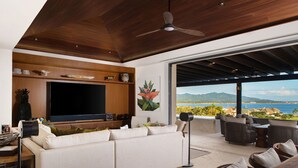 A modern living room with a large flat-screen TV, a sofa, and a view of the ocean. - PH Prima Vista 4BD - Tau Punta Mita (Punta de Mita)
