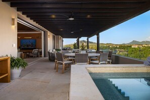 Eine überdachte Terrasse im Freien mit Pool, Essbereich und Blick auf die Landschaft.
