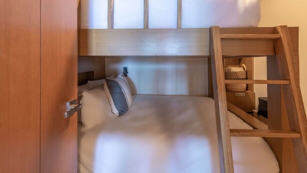 A bunk bed with a wooden ladder, a small shelf with baskets, and a door. - Rooftop Oasis 5BD - Surf Punta Mita (Punta de Mita)