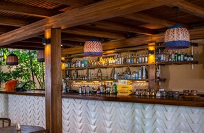 Eine Bar mit Holzbalken, hängenden Lampen und einer Auswahl an Spirituosenflaschen.