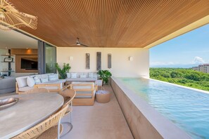 Ein moderner Außenbereich mit Pool, Sitzgelegenheiten und Blick auf die Landschaft.