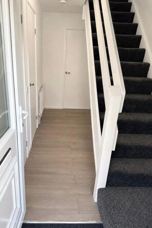 A staircase with a white handrail and carpeted steps leading to a door. - House Sleeps 7 with Parking and Garden (Nottingham)