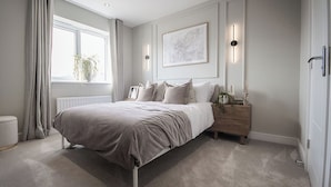 A bedroom with a bed, bedside tables, a window with curtains, a radiator, and a wall-mounted light fixture. - House - Sleeps 6 - Parking - Garden (Newcastle)