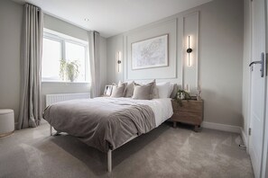 A bedroom with a bed, bedside tables, a window with curtains, a radiator, and a wall-mounted light fixture. - House - Sleeps 6 - Parking - Garden (Newcastle)