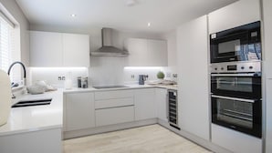 A modern kitchen with white cabinetry, a stainless steel range hood, and a double oven. - House - Sleeps 6 - Parking - Garden (Newcastle)