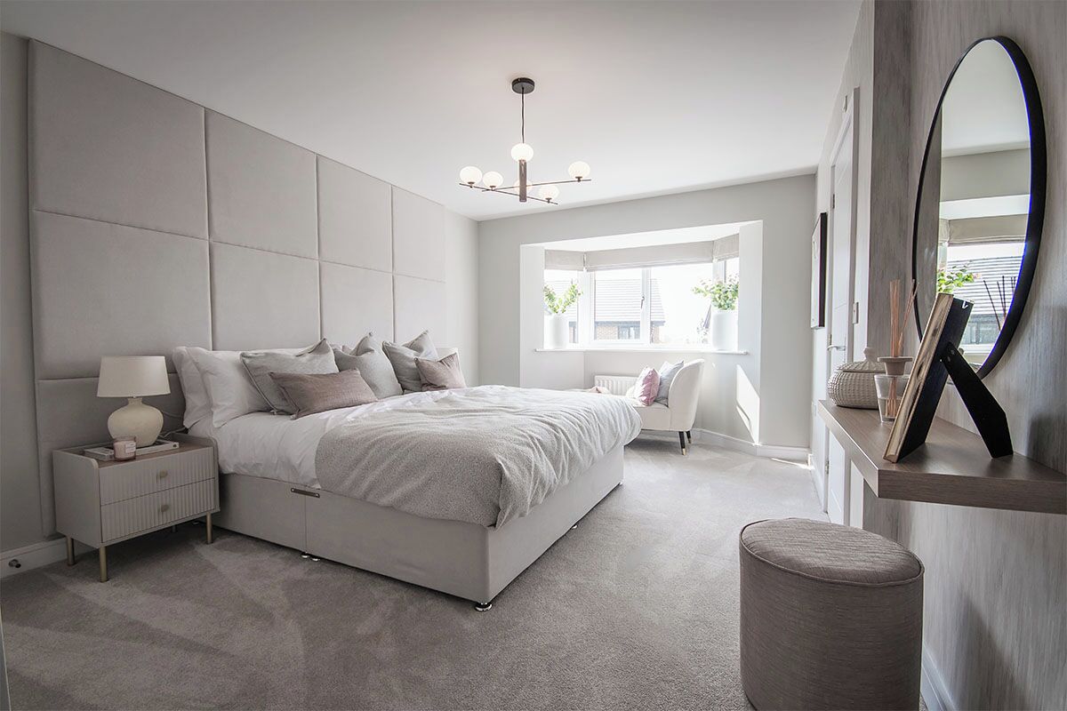 A modern bedroom with a large bed, bedside tables, a mirror, and a window with natural light.